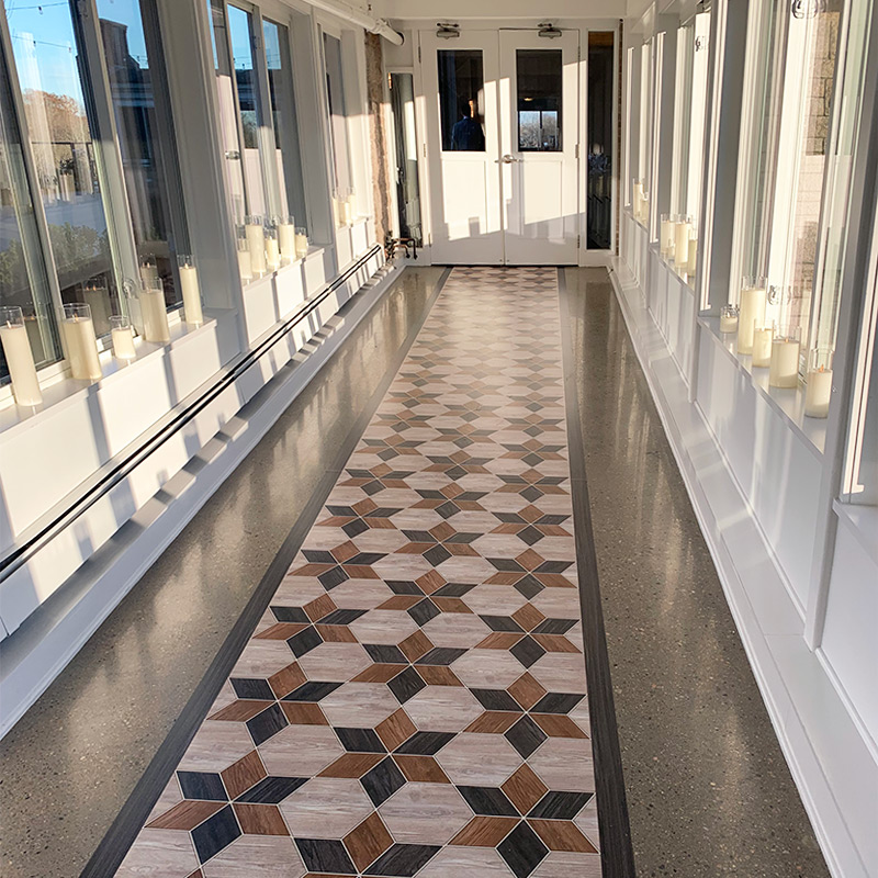 A vinyl floor wrap printed with an intricate wooden tile pattern creates a runner through the hallway leading from the foyer to the wedding's banquet hall.