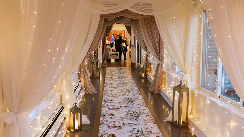 A vinyl floor wrap printed with a pattern of floral bouquets creates a runner leading from the reception hall to the banquet hall of this wedding venue.