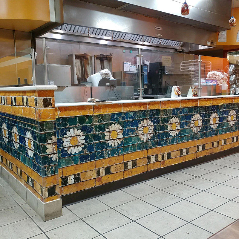 Mobile, Alabama's quick-serve Mediterranean Sandwich Co. achieved the high end look of Greek tile by using a custom wallcovering that gave them the same look at a much lower cost. The meal prep and service/check-out counter are beautifully wrapped.