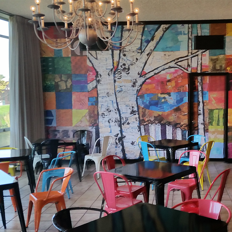 This cozy café and coffee shop in Hastings, Nebraska is decorated with the bright colors of an abstract forest scene in a wallpaper mural covering an entire dining room wall. It's vibrant décor even in the most gray of winters.