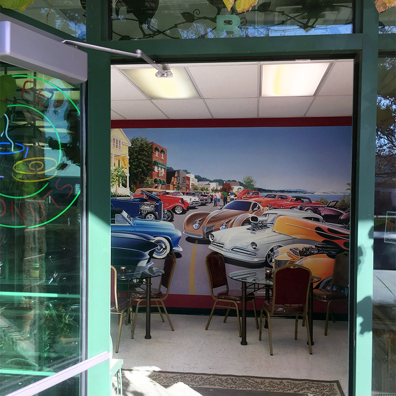Cafe Grand Prix in Salt Lake City chose a colorful mural of classic cars called “Car Show by Lake” by artist Bruce Kaiser (well known for his classic and vintage car artworks) to hang in their entryway and invite patrons in through their front doors.