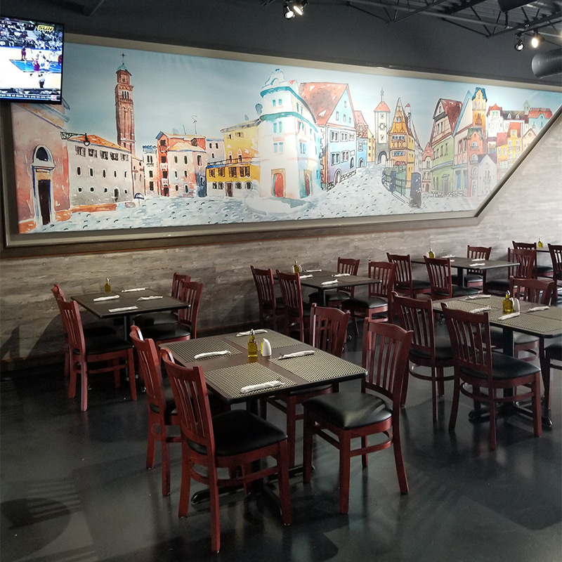 Pop's Pizza and Sports Bar has gone all in on giving its diners an Italian experience with a custom wallpaper mural featuring a panoramic illustration of a rural Italian village. The mural is framed in two panels to span the length of the dining room.