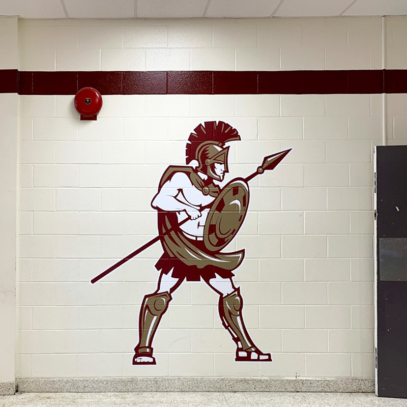 The Trojan is a rather common high school mascot. This large scale, die-cut wall decal graces a cinder block wall near the school athletics center at Harnett Central High School.
