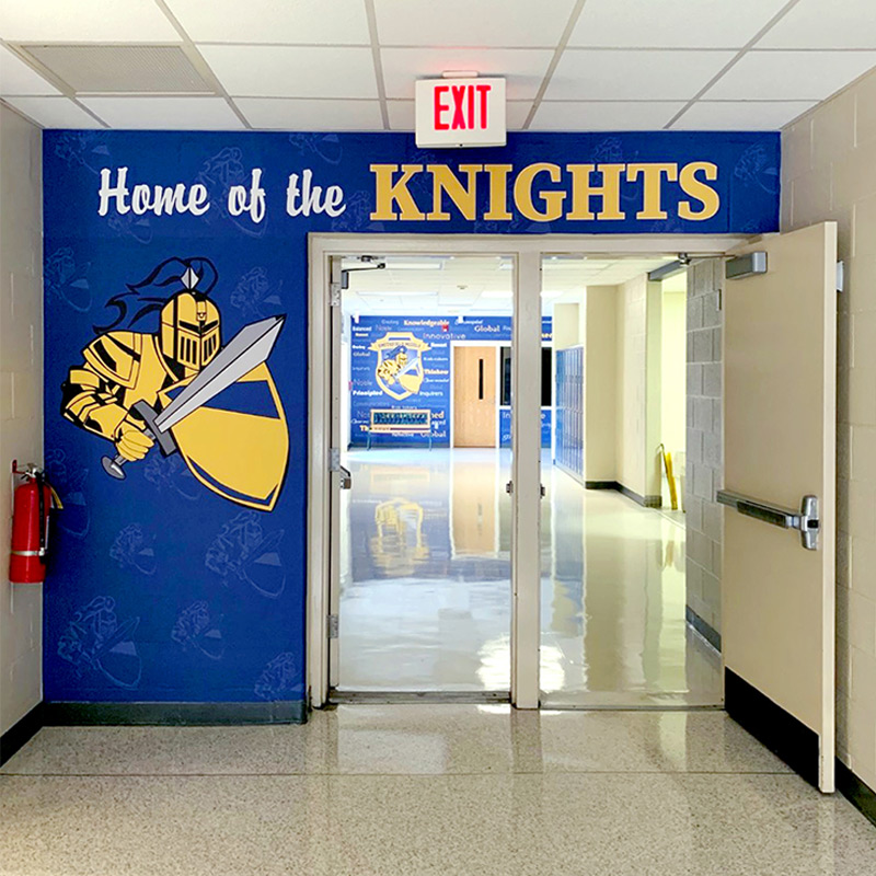 This wallpaper mural door surround indicates that Smithfield Middle School is clearly the home of the KNIGHTS! This wall wrap features the school mascot as a watermark step and repeat pattern in the background with a bold mascot graphic in the foreground.