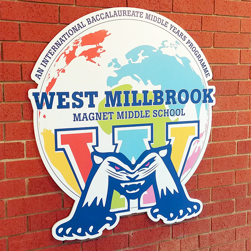 A die cut wall decal featuring the school’s mascot and logo is affixed to a contour cut rigid backing and attached to a brick wall at the entrance of West Millbrook Magnet Middle School.