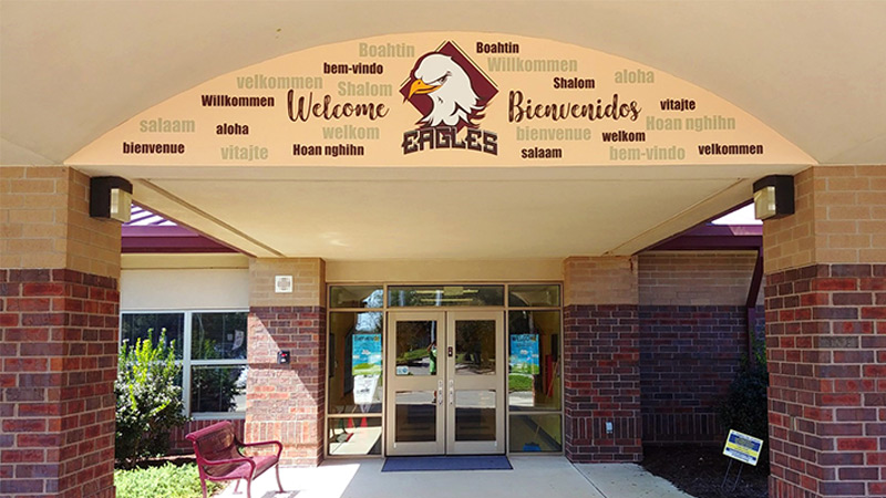 Harnett Primary School’s eagle mascot & word art expressing “welcome” in multiple languages greet visitors at the entry of the school.