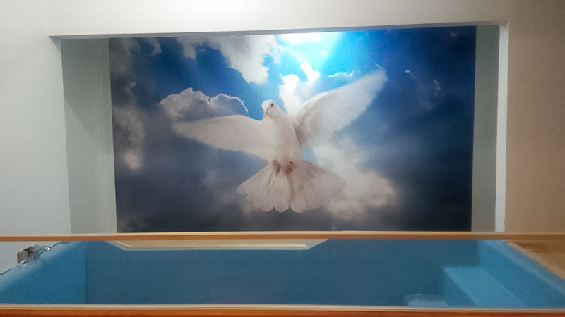 A wall mural featuring a white dove of peace adorns this church baptistry.