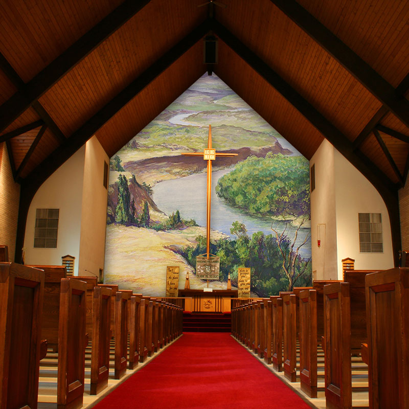 The custom printed wall mural wallpaper in the sanctuary and altar area of this church features a vintage print called the "Jordan River Valley." The shape of the mural mimics the shape of the steepled arch and soars to the heavens.