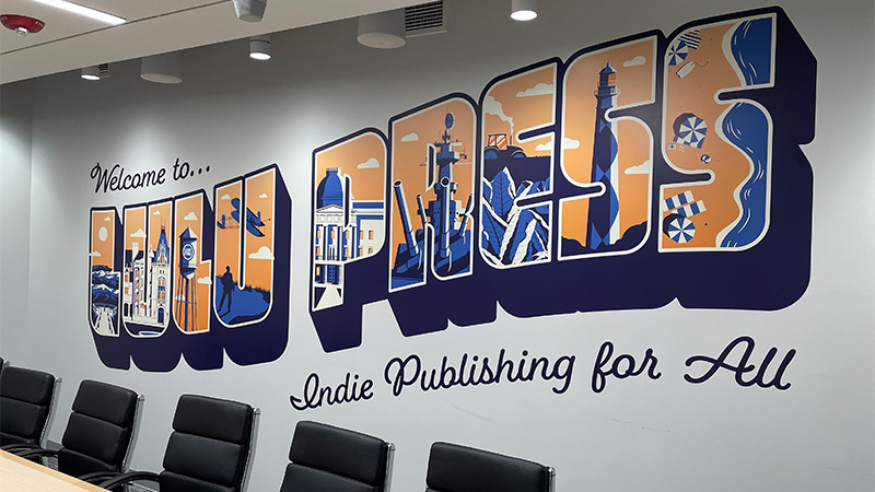 A company name has been turned into a colorful contour-cut aka die cut signage decorating a meeting and conference room.