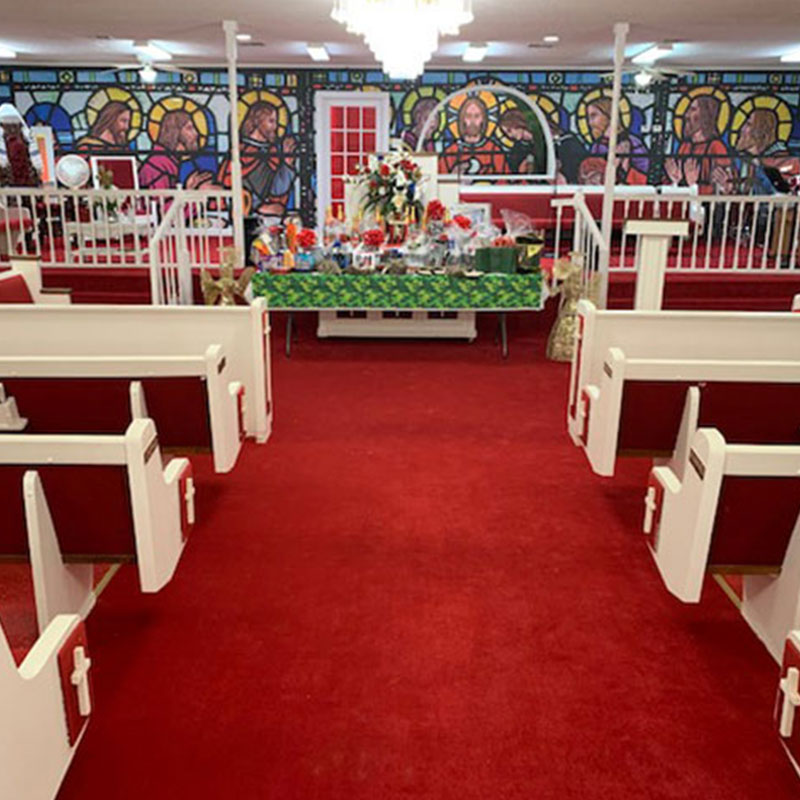 A stage backdrop at the Word of Faith Church is covered in a wallpaper mural that looks just like stained glass depicting Jesus and His Apostles.