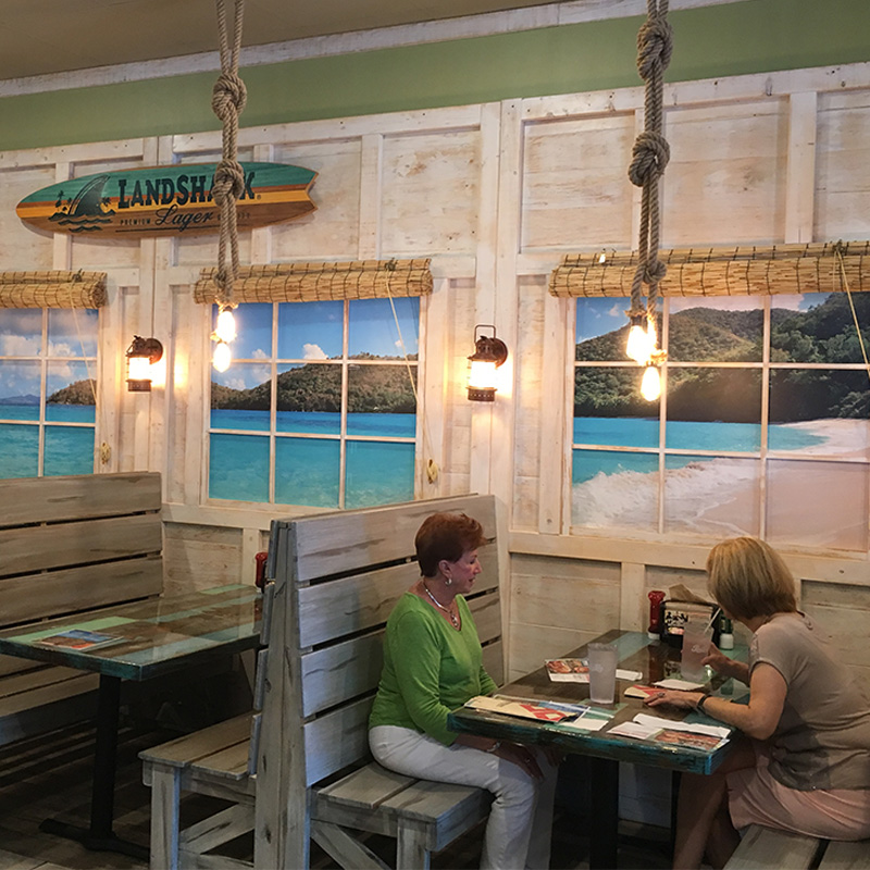 When your fast-casual restaurant chain is called Hurricane Grill and Wings you know that the interior will have a beach hut kind of vibe. That's was achieved by installing a tropical beach view wallpaper mural behind the faux windows at every booth. When your fast-casual restaurant chain is called Hurricane Grill and Wings you know that the interior will have a beach hut kind of vibe. That's was achieved by installing a tropical beach view wallpaper mural behind the faux windows at every booth.