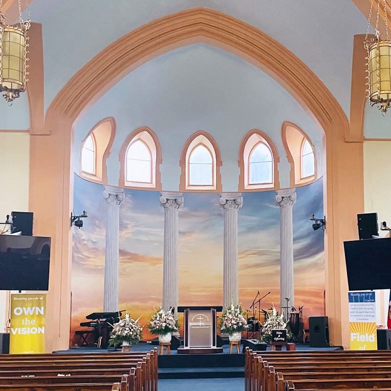 A full wall mural depicting a glorious dawn sunrise makes it always look like a new day is just beginning in the church sanctuary and main worship stage at the Shekinah Worship Center.