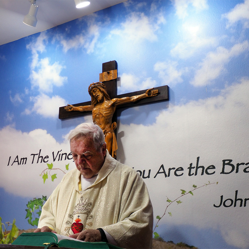 The Reverend James Harnon stands in front of a custom wall mural in the sanctuary of his church in Blanco, TX. A cloud mural from our collection was customized with Bible verse John 15:5 from the Book of John.
